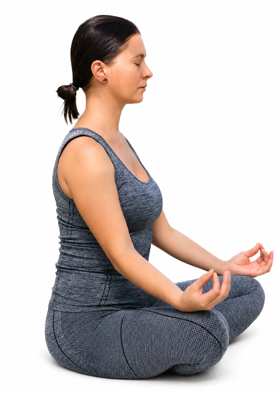 Žena v modrém sportovním overalu sedí v lotosové pozici, zavřené oči, ruce v gestu meditace.
